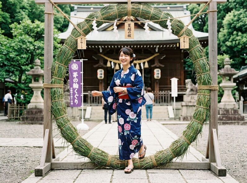 神社で茅の輪くぐりをする女性