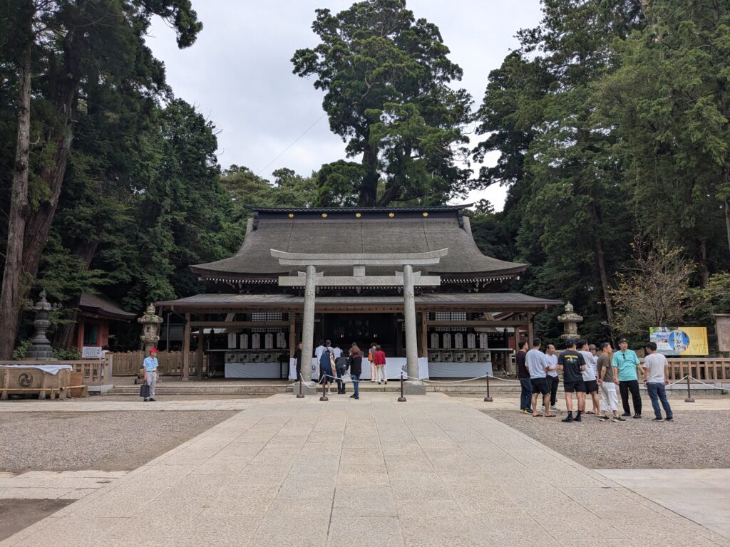 石鳥居の正面に建つ大きな拝殿と参拝者のいる神社境内