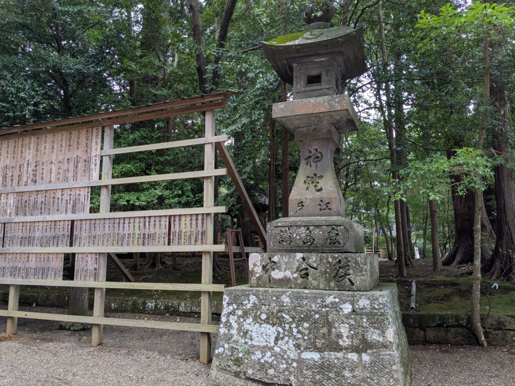緑豊かな神社境内に残る文字が刻まれた古い石灯籠