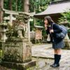 神社の狛犬を眺める女性