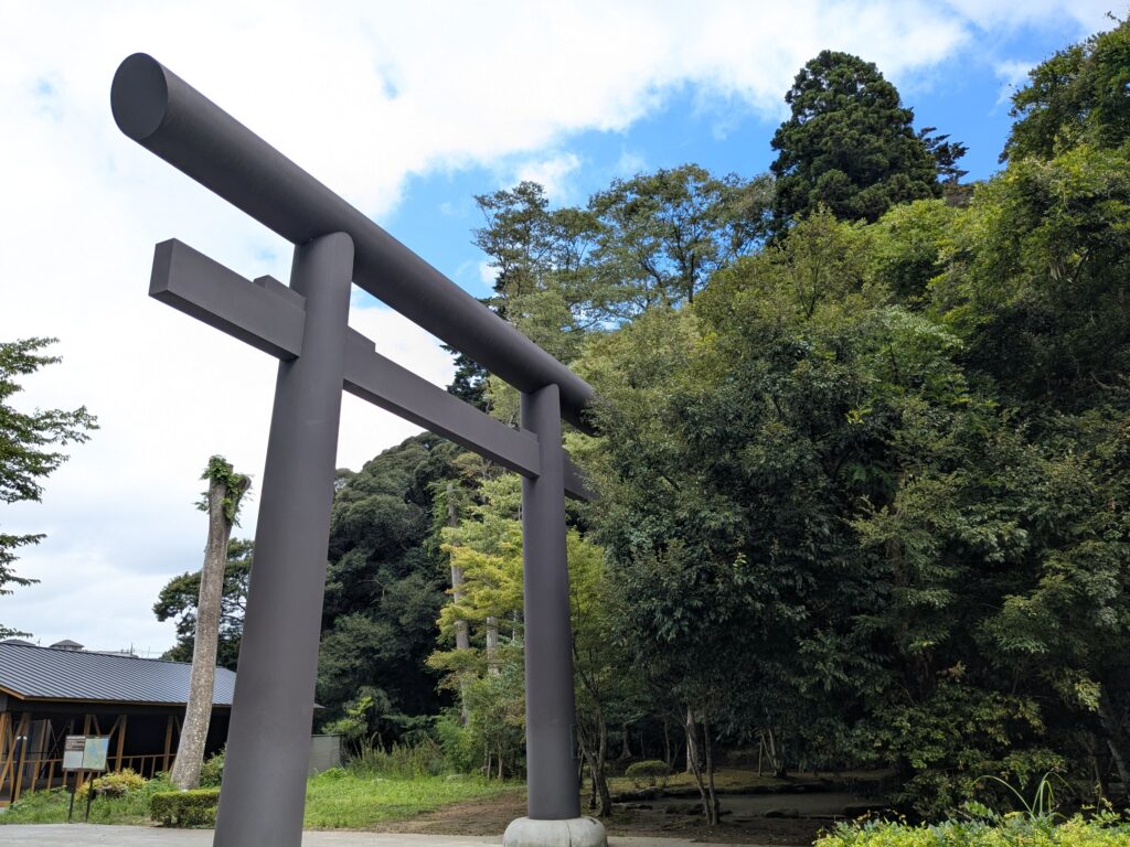 青空と緑豊かな森を背景に立つ大きな鳥居