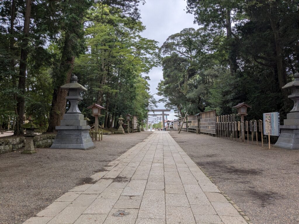 石灯籠と大木に囲まれてまっすぐ延びる神社の石畳の参道