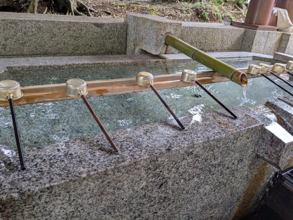 神社参拝前に手と口を清める石造りの手水鉢と柄杓