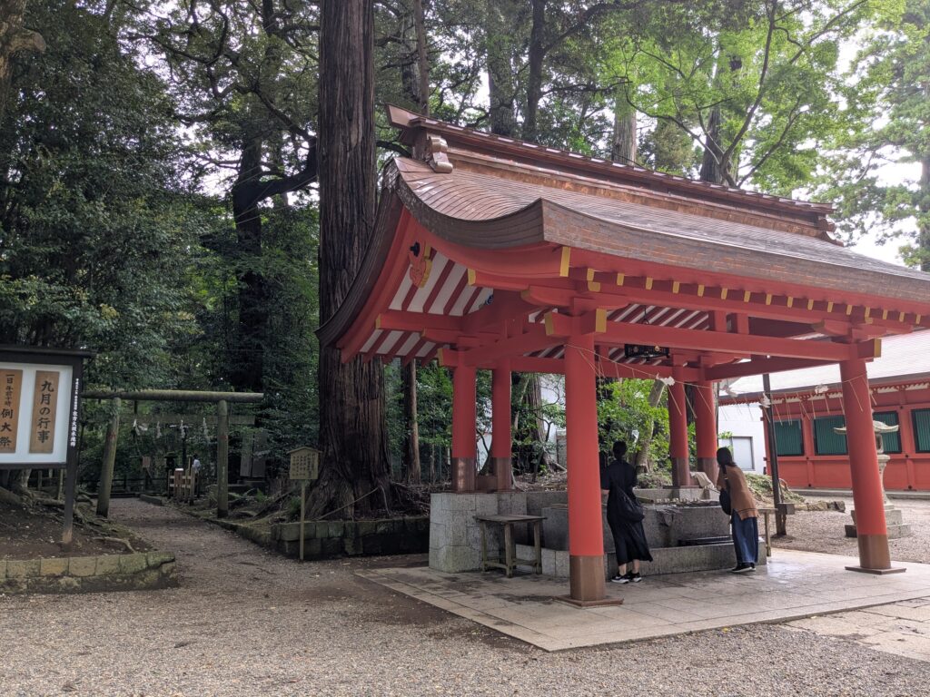 朱色の柱と反りのある屋根を持つ神社の手水舎